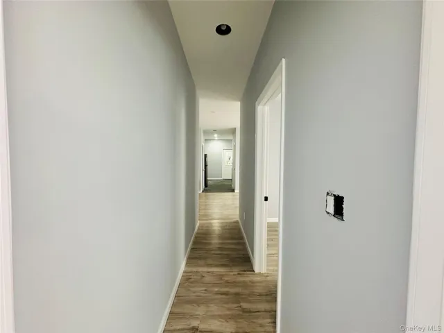 a view of a hallway with wooden floor and a bathroom