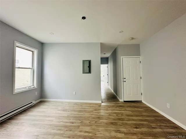 a view of an empty room with window and wooden floor
