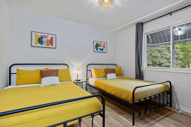 a bedroom with 2 bed and a large window