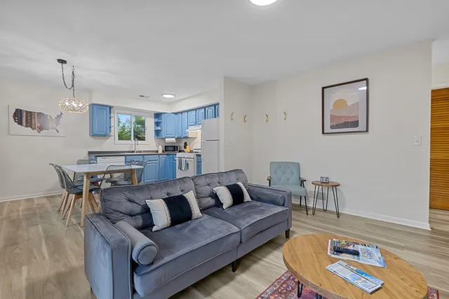 a living room with furniture and a dining table with wooden floor