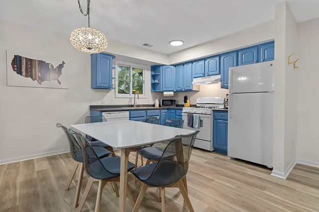 a kitchen with stainless steel appliances granite countertop a dining table chairs and a refrigerator