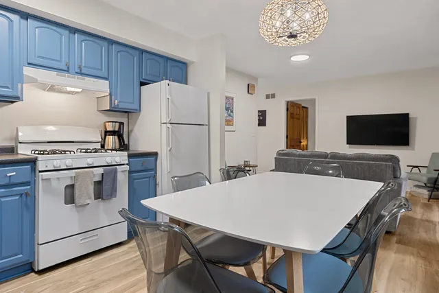 a kitchen with stainless steel appliances a stove a refrigerator a sink a dining table and chairs