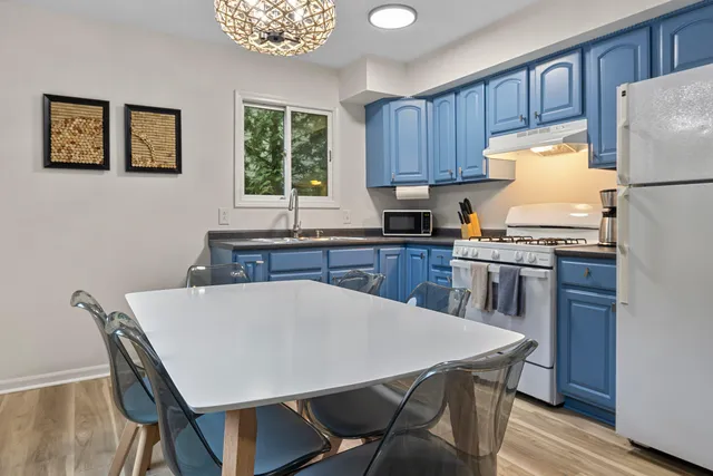 a kitchen with stainless steel appliances granite countertop a stove a refrigerator a sink dishwasher a dining table and chairs with wooden floor