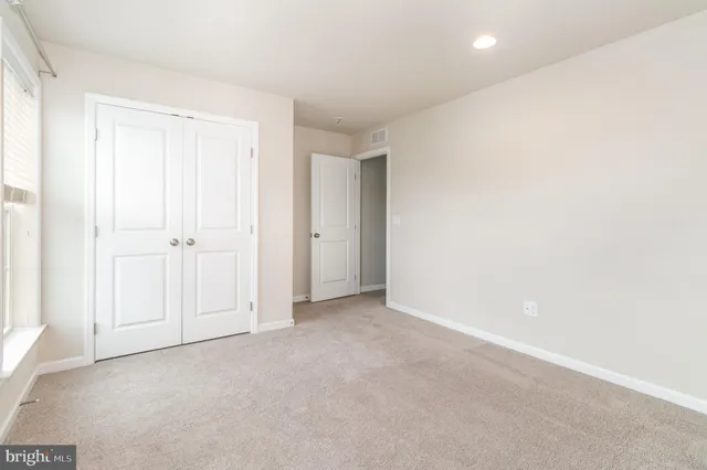 an empty room with white cabinet and mirror