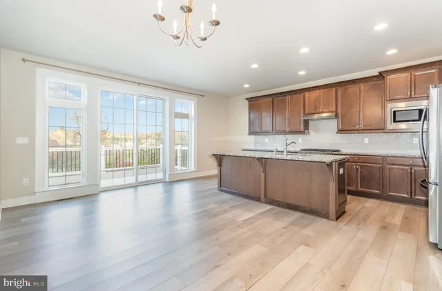 a large kitchen with stainless steel appliances granite countertop a stove a sink dishwasher a microwave oven with cabinets and wooden floor