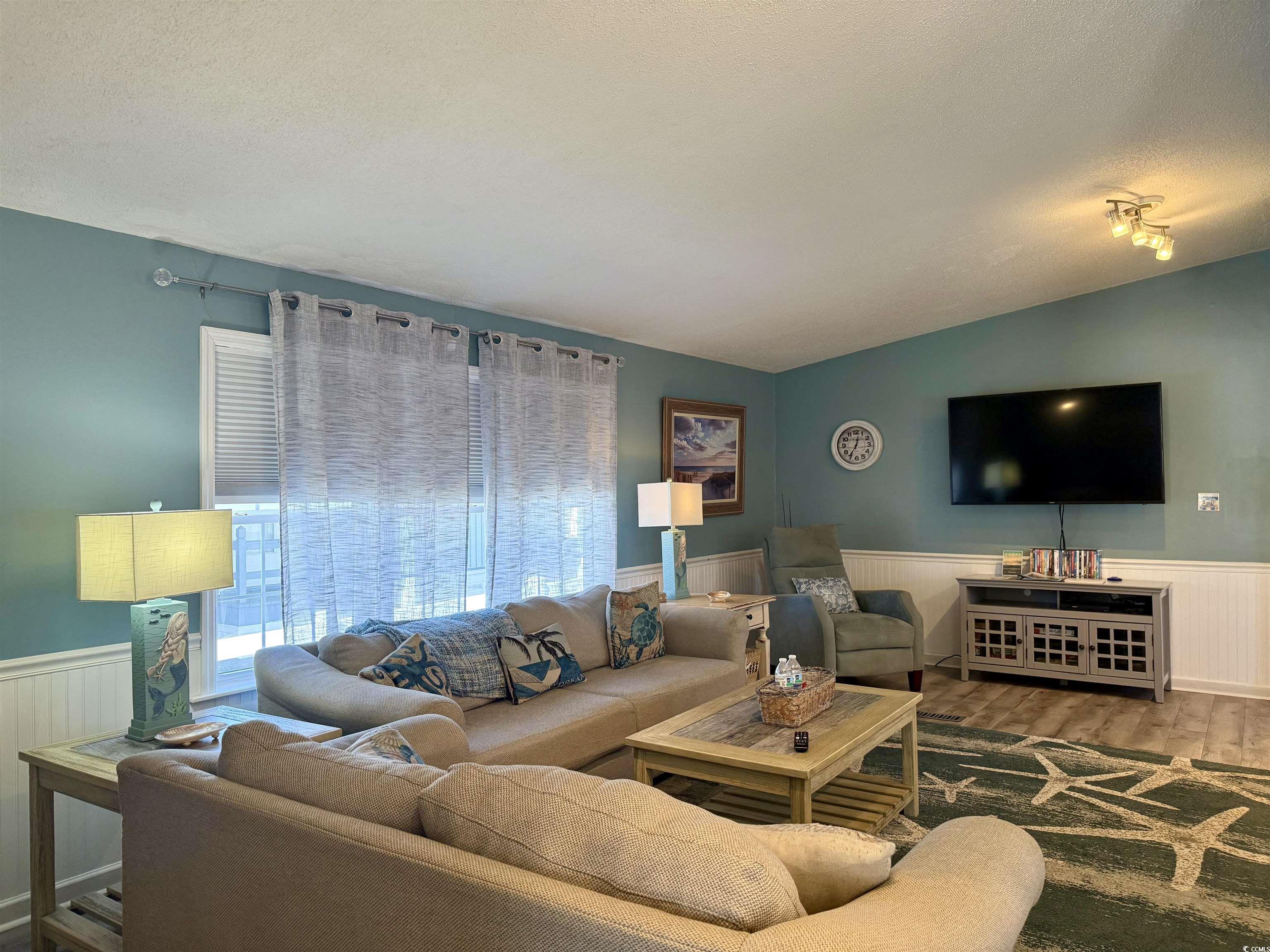 427 Meadowlark Surfside Beach, SC 29575 - Photo 11 of 33 Living room featuring a wainscoted wall, vaulted ceiling, wood finished floors, and a textured ceiling