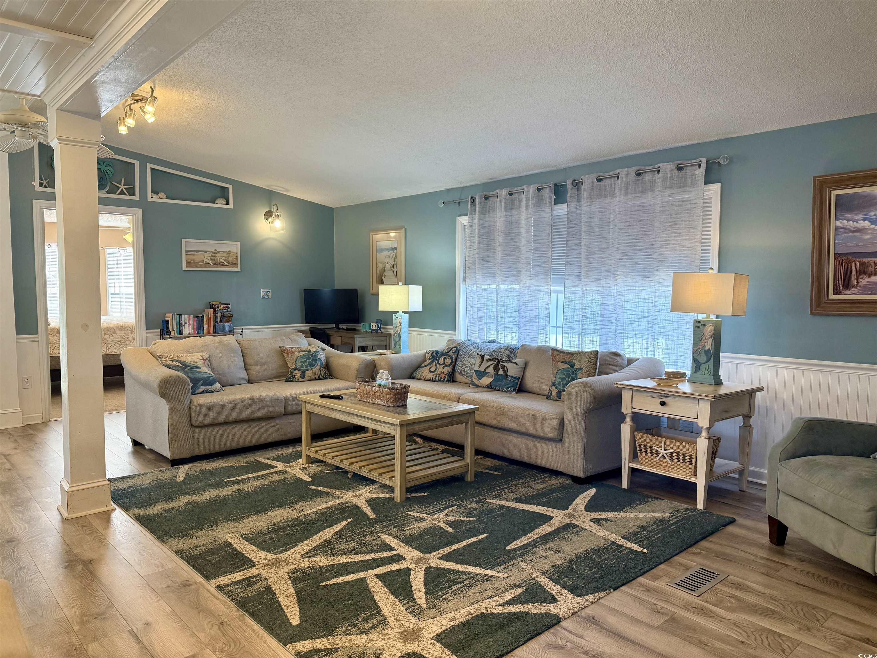 427 Meadowlark Surfside Beach, SC 29575 - Photo 12 of 33 Living area featuring lofted ceiling, a textured ceiling, wainscoting, wood finished floors, and ceiling fan