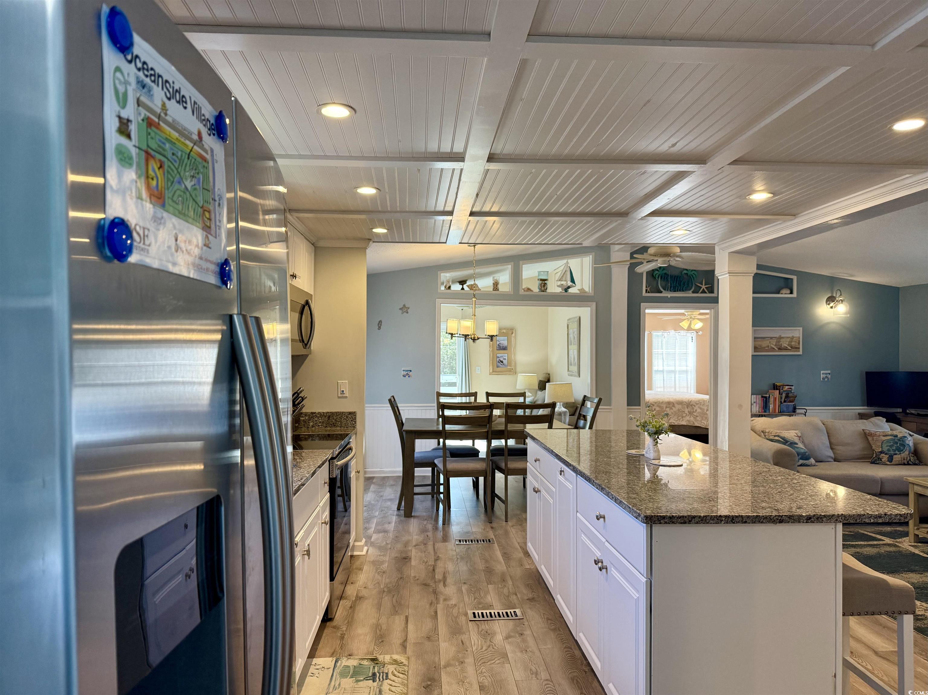427 Meadowlark Surfside Beach, SC 29575 - Photo 32 of 33 Kitchen with appliances with stainless steel finishes, white cabinetry, open floor plan, dark stone countertops, and light wood-style floors