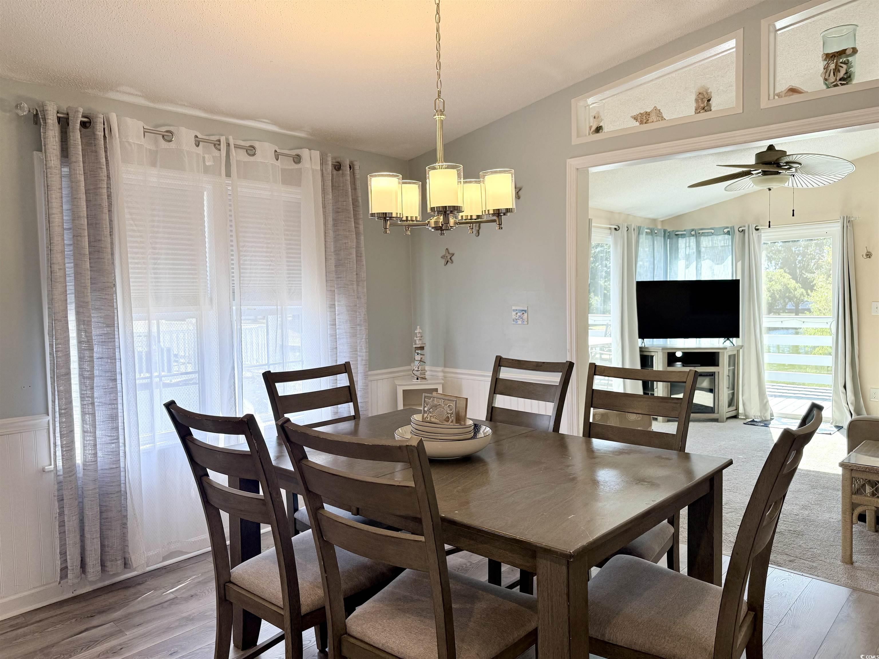 427 Meadowlark Surfside Beach, SC 29575 - Photo 4 of 33 Dining space featuring lofted ceiling, wainscoting, a ceiling fan, a chandelier, and wood finished floors