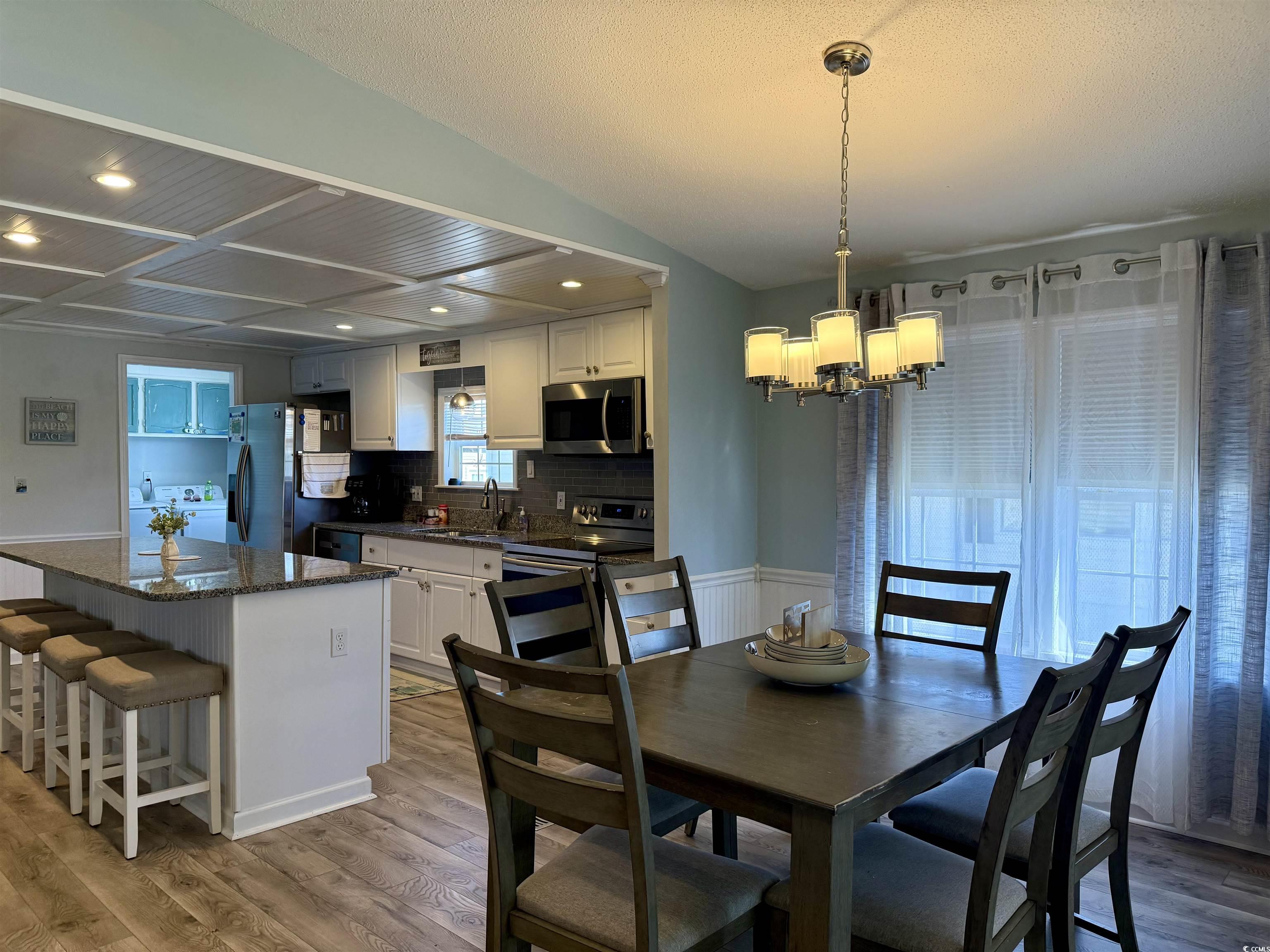 427 Meadowlark Surfside Beach, SC 29575 - Photo 7 of 33 Dining space with light wood finished floors, a chandelier, recessed lighting, coffered ceiling, and wainscoting