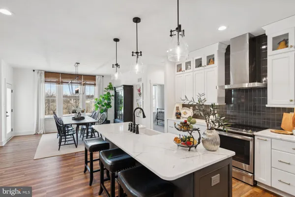 a kitchen with stainless steel appliances a dining table chairs stove refrigerator and cabinets