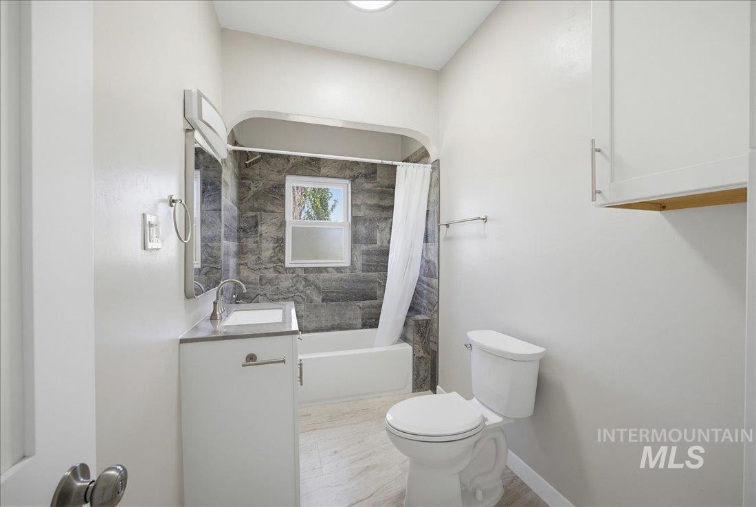 30013 Apple Valley Road Parma, ID 83660 - Photo 22 of 25 Bathroom featuring a shower-tub combination with dark tile surround, a single vanity with an integrated sink, a wall-mounted mirror, and wood-finish flooring