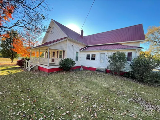 a view of a white house with a small yard and large tree