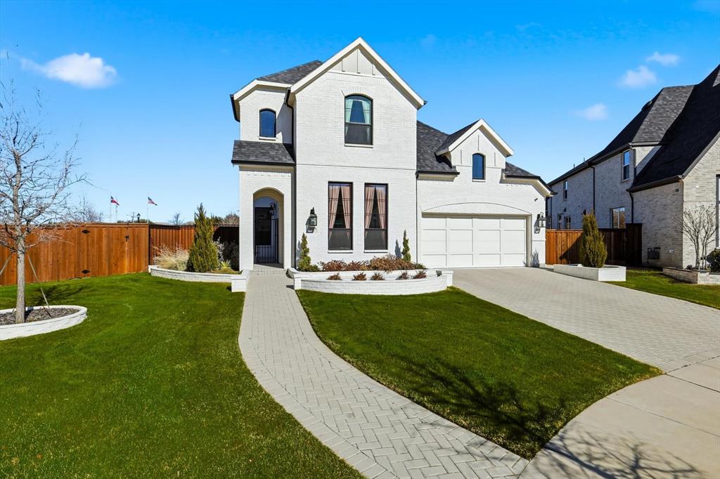 Painted brick facade featuring driveway, a garage, and painted brick planters