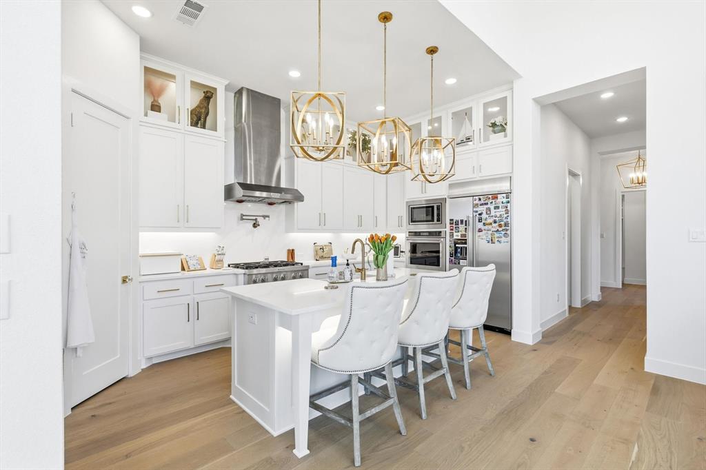 16194 Inca Dove Court Frisco, TX 75035 - Photo 12 of 40 Bespoke Kitchen with upgraded wood flooring, designer lighting, KitchenAid appliances and stacked upper cabinetry.