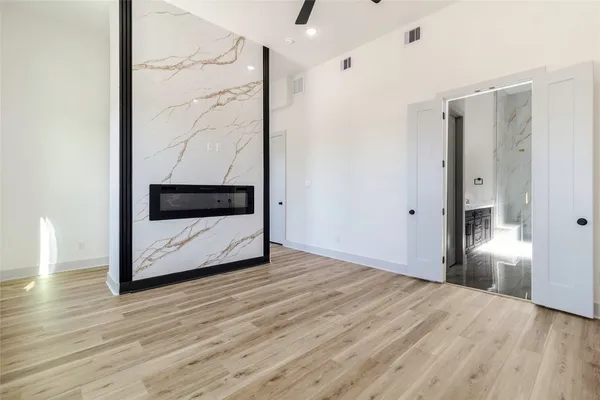 a view of an empty room with wooden floor and a bathroom