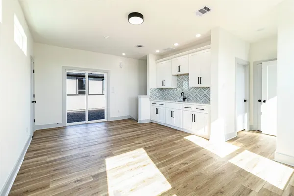 a large white kitchen with a sink and dishwasher with wooden floor