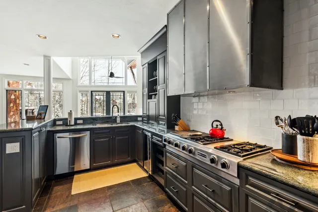 a kitchen with stainless steel appliances granite countertop a stove a sink dishwasher and cabinets with wooden floor