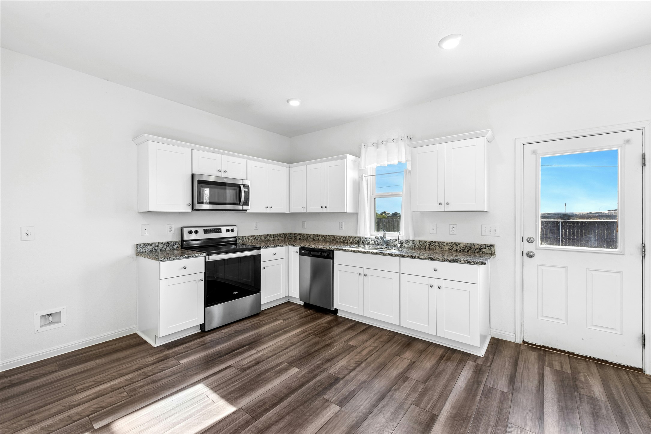 566 Delta Crest Maxwell, TX 78656 - Photo 7 of 27 Kitchen with appliances with stainless steel finishes, white cabinetry, dark wood-type flooring, dark stone counters, and recessed lighting