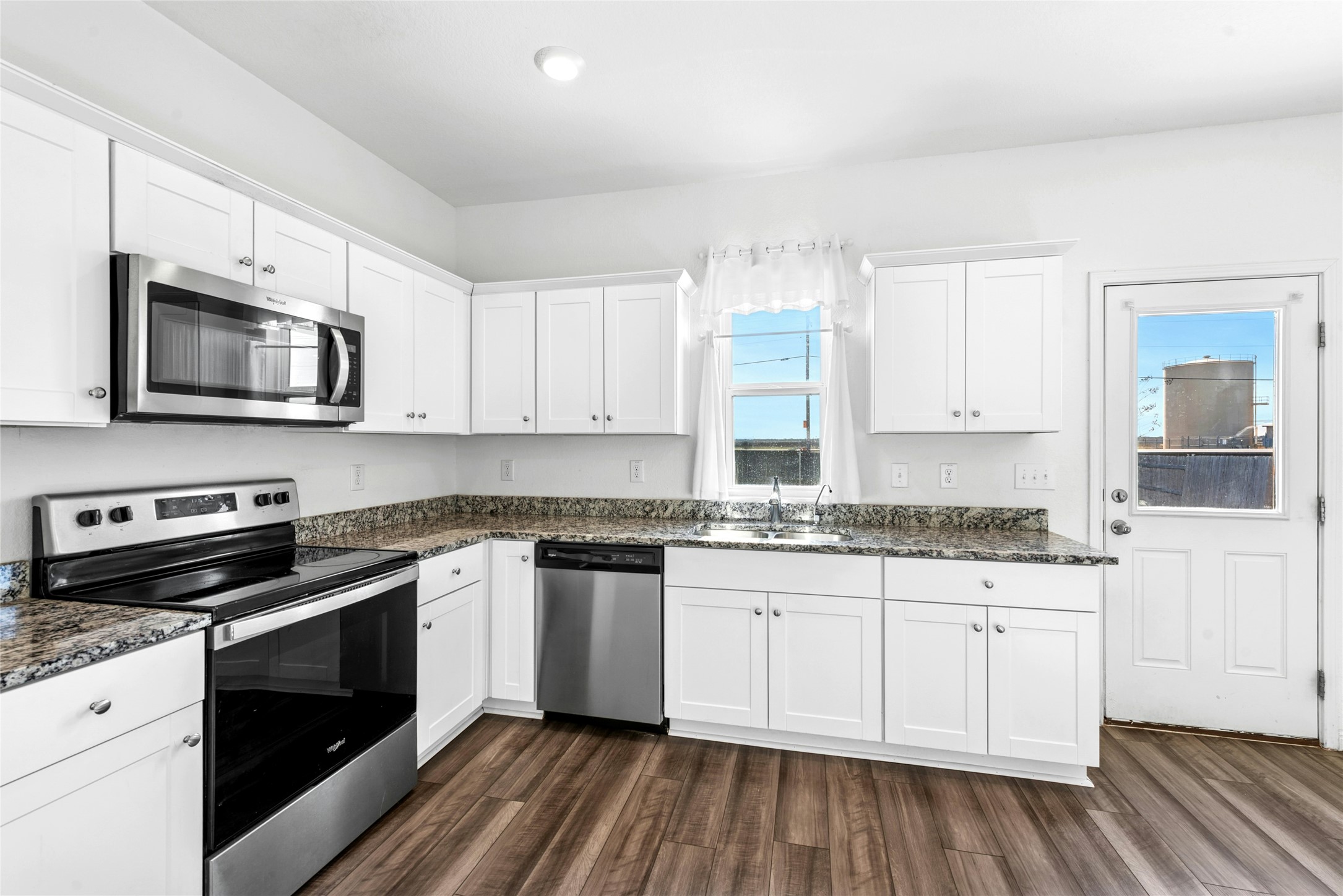 566 Delta Crest Maxwell, TX 78656 - Photo 8 of 27 Kitchen with stainless steel appliances, white cabinetry, dark wood finished floors, and dark stone countertops