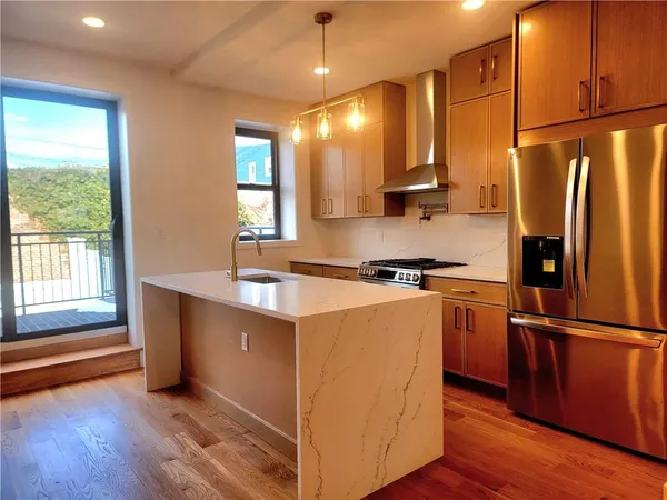 a kitchen with stainless steel appliances granite countertop a refrigerator a sink dishwasher a stove and a refrigerator with wooden floor