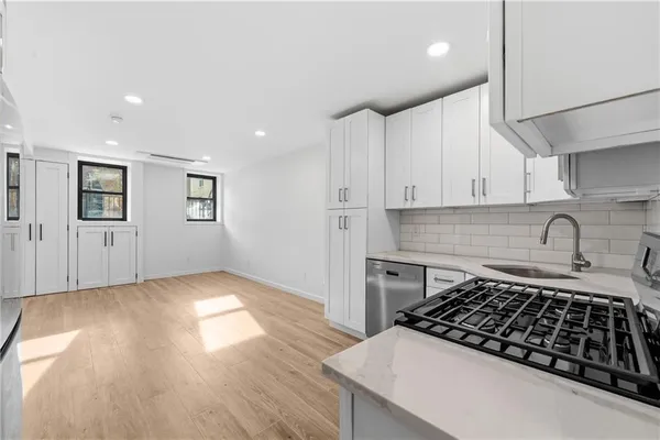 a kitchen with granite countertop a stove and white cabinets