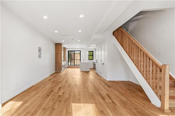 a view of a hallway with wooden floor and staircase