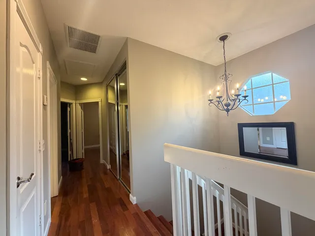 a view of a hallway to a livingroom with wooden floor and chandelier