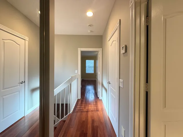 a view of a hallway with wooden floor and a door