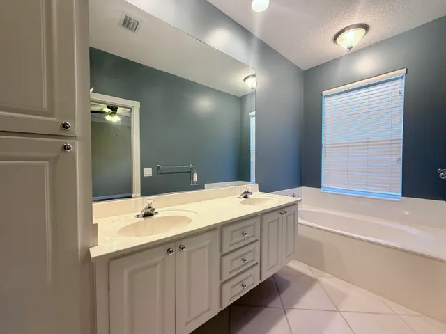 a bathroom with a tub a sink and mirror