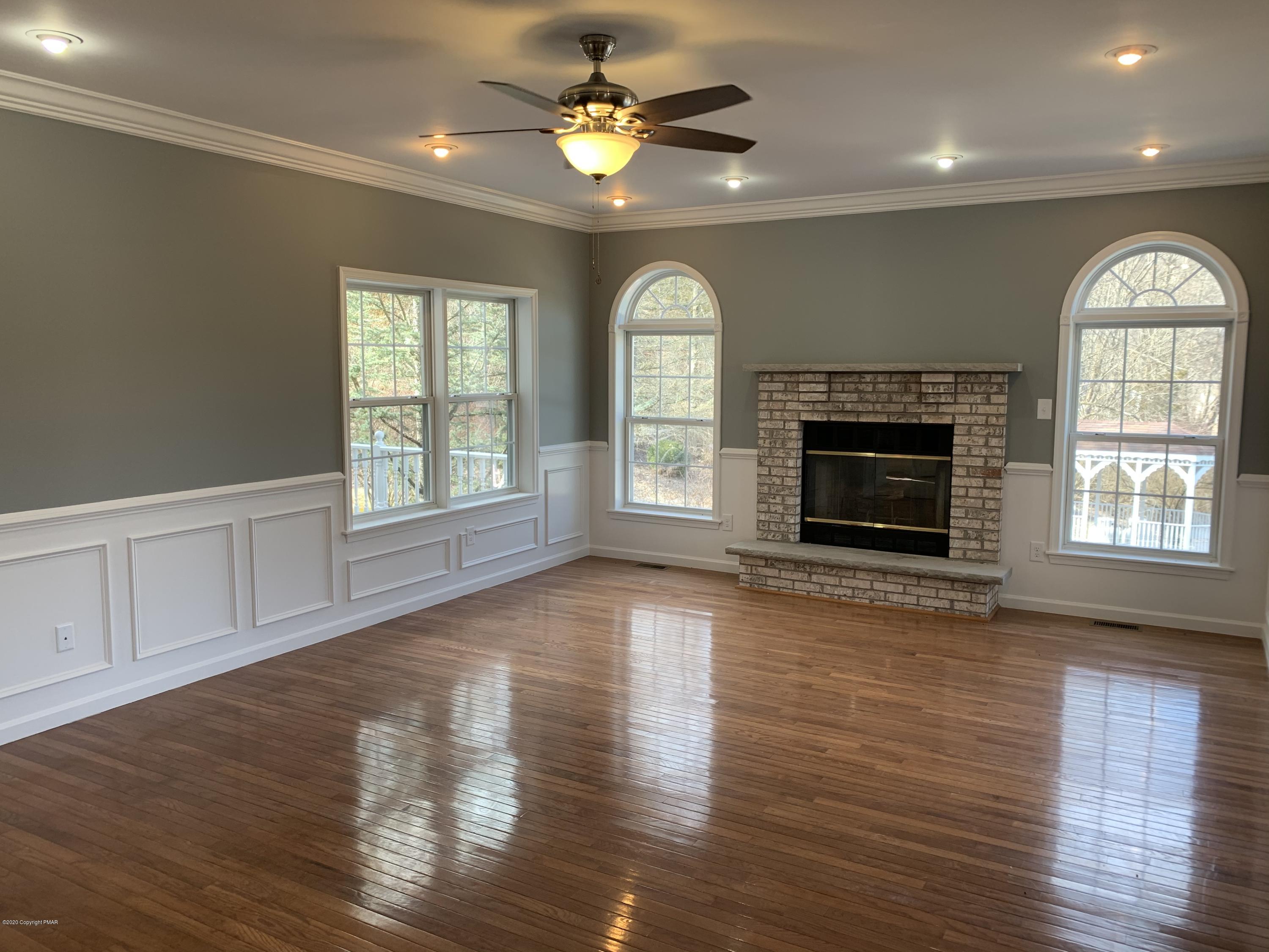 1697 Middle Road Stroudsburg, PA 18360 - Photo 62 of 116 an empty room with wooden floor a fireplace a ceiling fan and windows