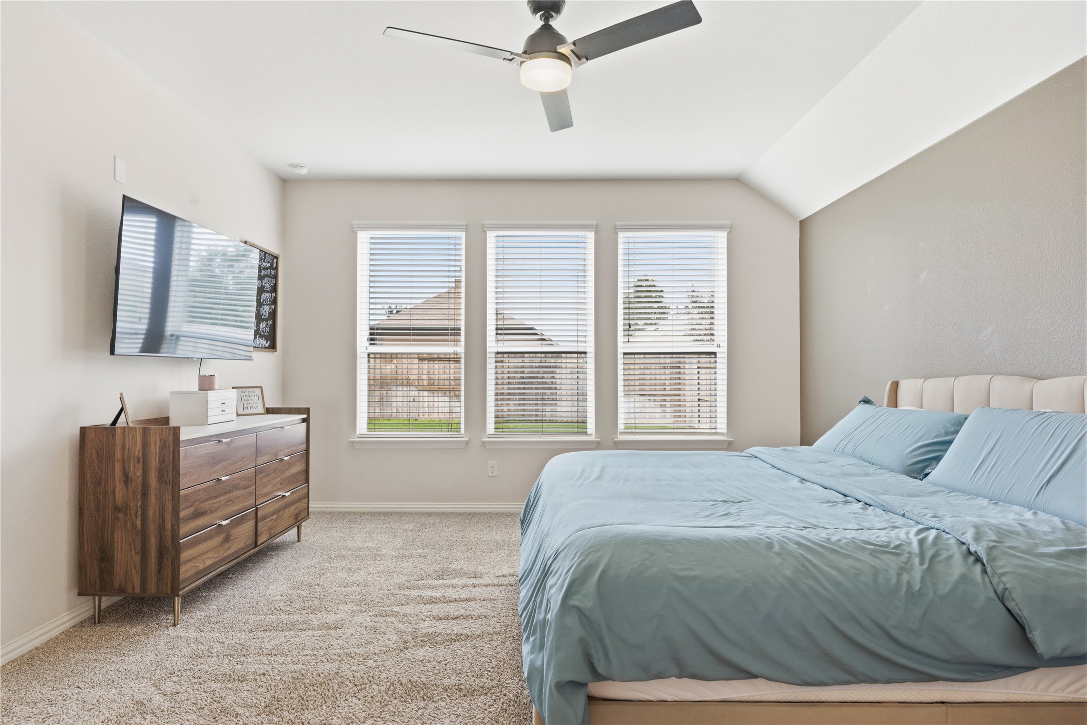 486 Pond View Pass Buda, TX 78610 - Photo 30 of 39 Room featuring a tray ceiling with a ceiling fan, three windows with blinds, and light-colored carpeting