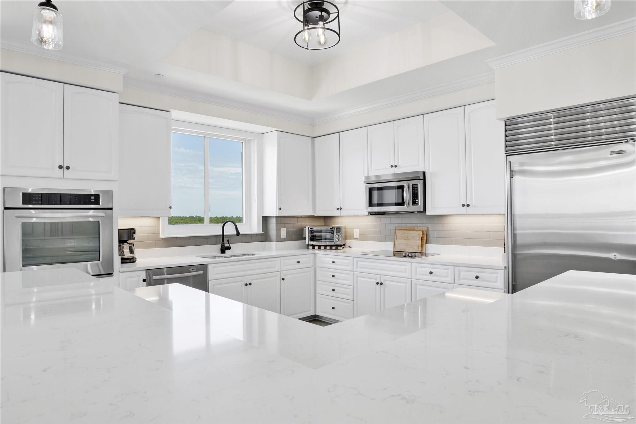 14500 River Road, Unit 507 Pensacola, FL 32507 - Photo 5 of 56 a large white kitchen with granite countertop a stove a sink a refrigerator and white cabinets with wooden floor