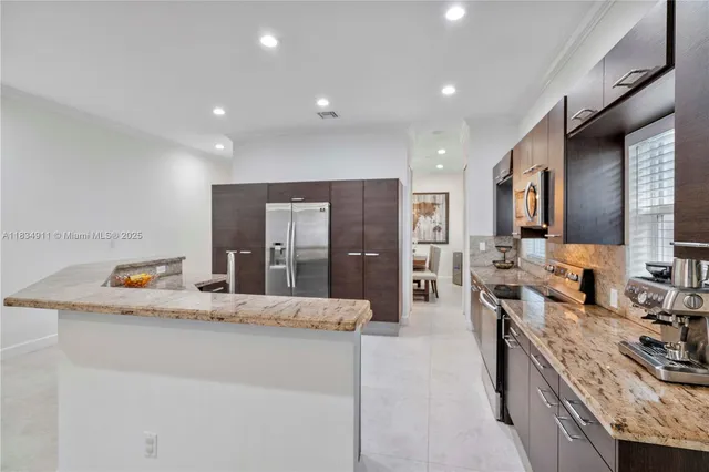 a large kitchen with granite countertop a large counter top cabinets appliances and a sink