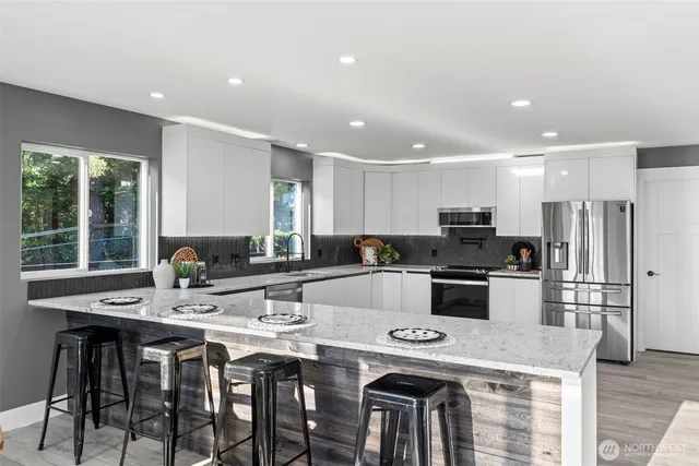 a kitchen with a dining table cabinets appliances and wooden floor