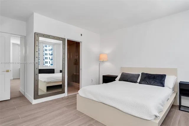 a bedroom with a large bed and wooden floor