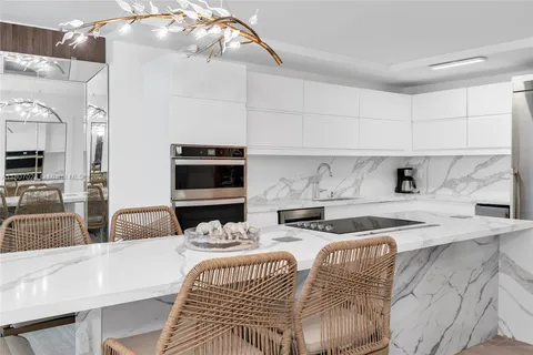 a kitchen with stainless steel appliances kitchen island granite countertop a sink and a white cabinets