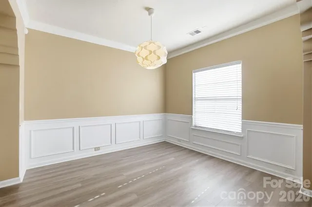 a view of an empty room with wooden floor and windows
