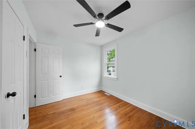 an empty room with windows and fan