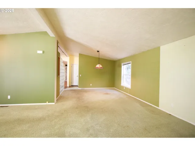 a view of a big room with wooden floor and windows