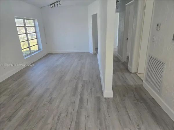 an empty room with wooden floor and windows