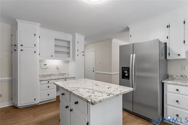 a kitchen with a granite countertop kitchen island a refrigerator a sink and wooden floor