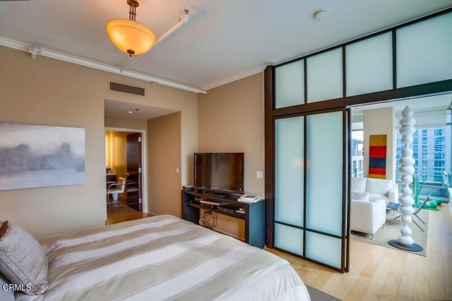 a bedroom with a bed and a flat tv screen on dresser