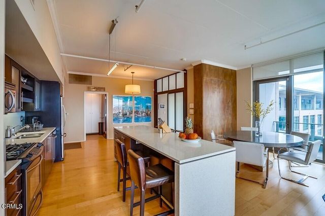 a open kitchen with stainless steel appliances a table and chairs in it