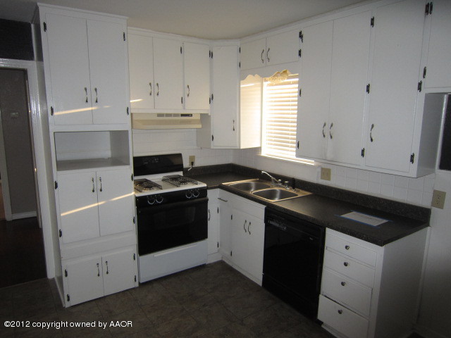 4114 Parker Street Amarillo, TX 79110 - Photo 13 of 15 a white kitchen with granite countertop white cabinets and black stove top oven with granite countertops