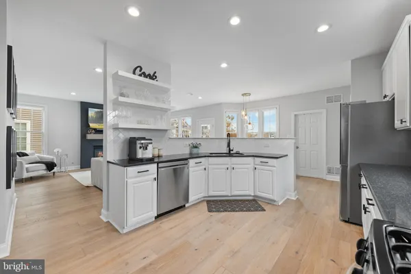 a kitchen with stainless steel appliances granite countertop a stove top oven a refrigerator a sink and a center island