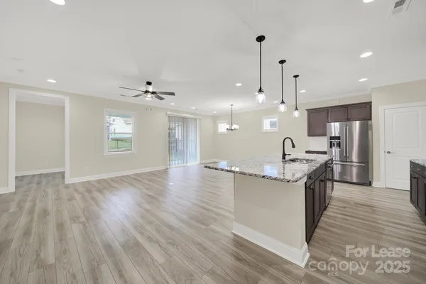 a kitchen with stainless steel appliances kitchen island wooden floors cabinets and dining table