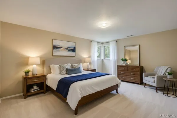 a spacious bedroom with a bed a couch and dresser