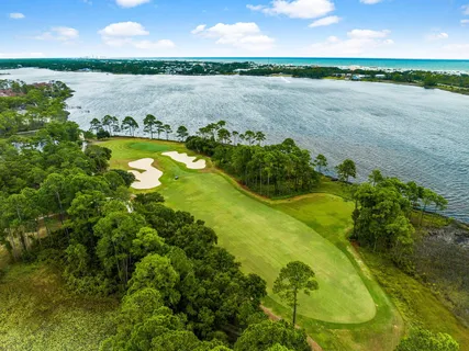 a view of a lake with lawn chairs and large trees
