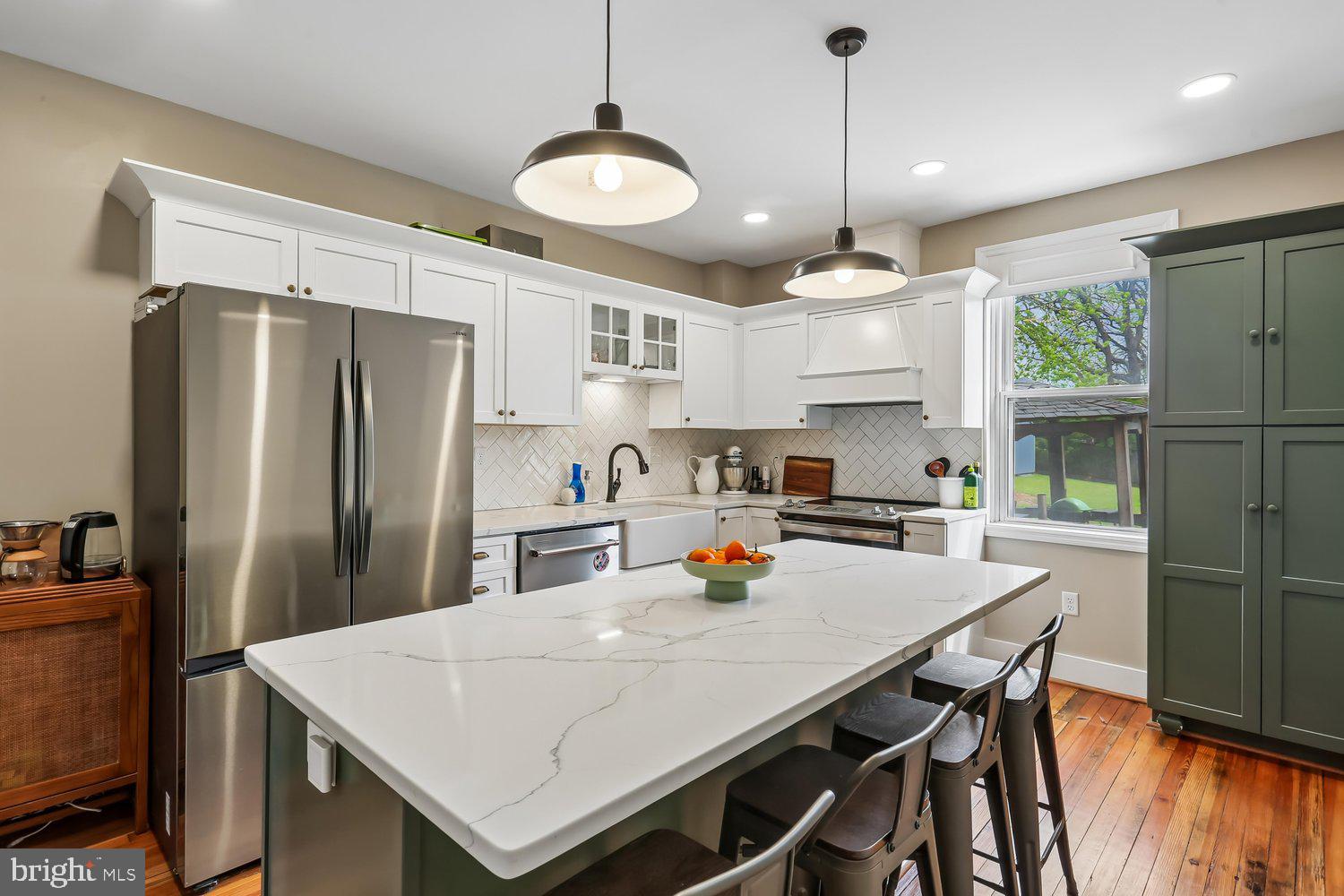 30 Hamilton Avenue Frederick, MD 21701 - Photo 12 of 37 a kitchen with stainless steel appliances granite countertop a sink a stove a refrigerator a center island a refrigerator a stove and a dining table with wooden floor